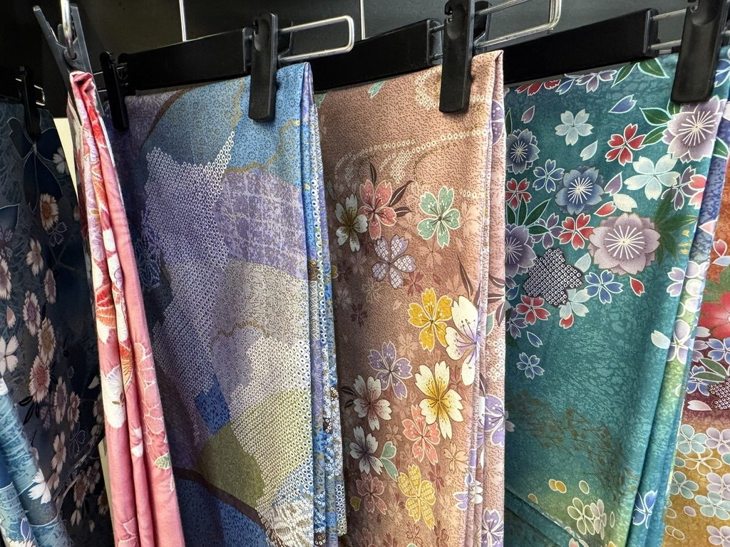 Floral Japanese kimono fabrics in teal, pink, and lavender hanging on clips