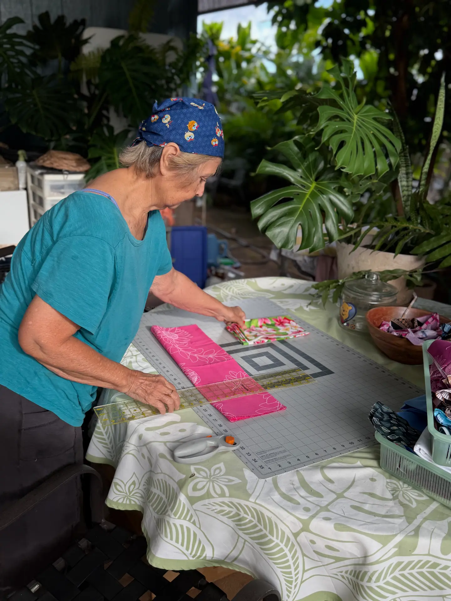 Tutu Lu cutting Hawaiian print fabric at her outdoor sewing table