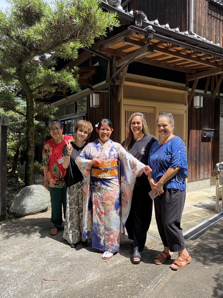 Group of friends and family in front of a traditional Japanese home, one in kimono