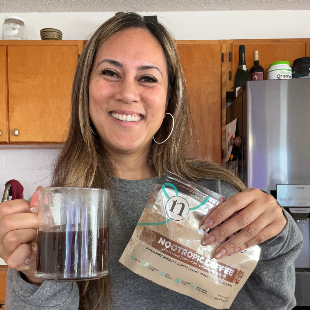 Brandy holding a mug of coffee and a bag of Nootropic Coffee